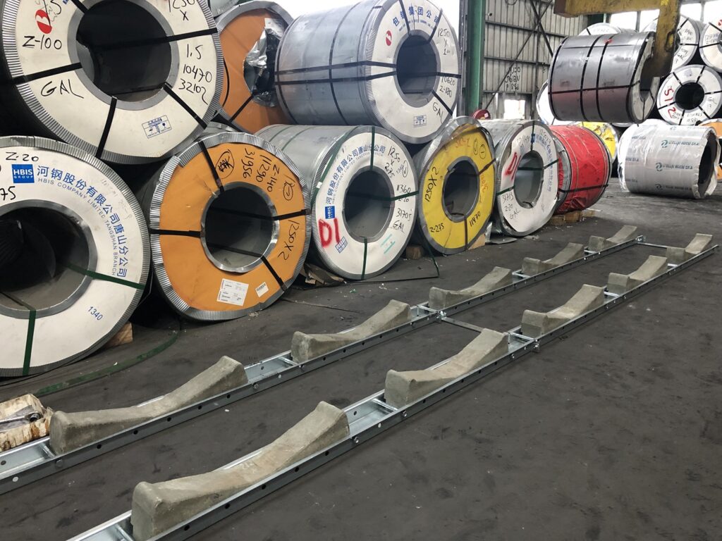 PKT Rollcradle system for safe storage of coils up to two levels. The picture shows both unsafe multi-level storage with only wooden blocks stopping them from moving and a new, safe, Rollcradle system in the foreground.