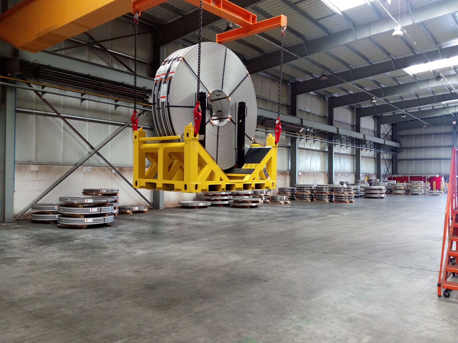 UTLS Systems coil transportation rack with UTLS stanchions Vario and restraint system for thin slit coils. The rack is lifted in the overhead crane by help of the UTLS Vario lifting beam.